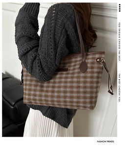 Side view of checkered tote bag with brown leather handles and gold metal rings