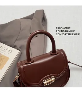 Detail of round top handle and golden twist lock on brown leather saddle bag