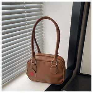 Detail of brown pebble texture faux leather shoulder bag with a heart charm and top zipper