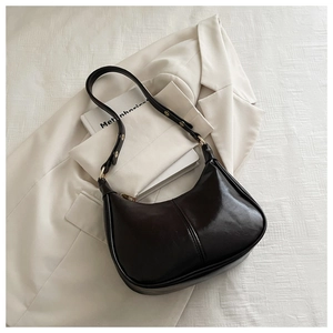 Close-up of a dark brown wax leather crossbody bag with a moon shape and sleek texture