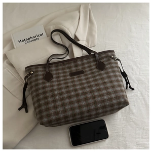 Detail view of vintage plaid tote bag with leather handles and side tassel accents