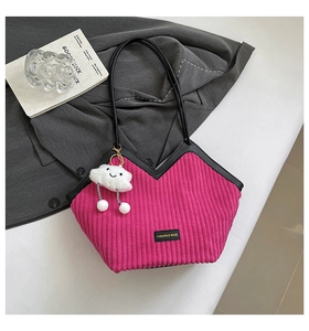 Detailed texture of magenta corduroy tote bag with black leather trim and plush charm