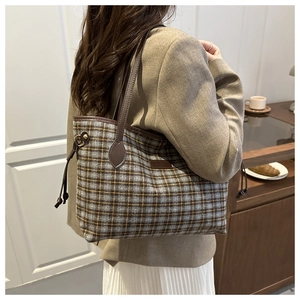 Detail of vintage plaid tote bag with brown leather trim shown on a model's shoulder