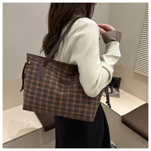 Detailed side view of vintage plaid tote bag with brown leather trim and side drawstring