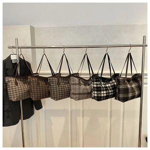 Close-up of textured plaid tote bags in various autumn colors with sleek dark straps