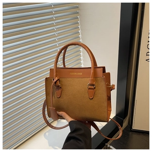 Detail of brown dual-texture tote bag featuring gold lettering and premium hardware