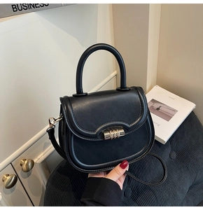 Detail of black matte saddle bag with a luxury gold cylindrical rotating clasp lock
