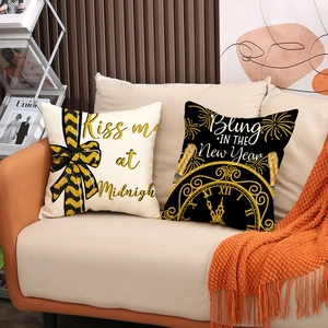 Set of two black and gold Happy New Year pillow covers on a cozy sofa setting