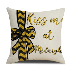 Close-up of beige linen pillow cover featuring gold Kiss me at Midnight text and black bow