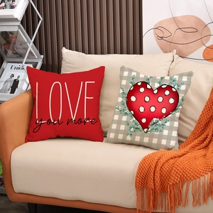 Detail of red LOVE and plaid heart cushion covers on a modern beige fabric sofa