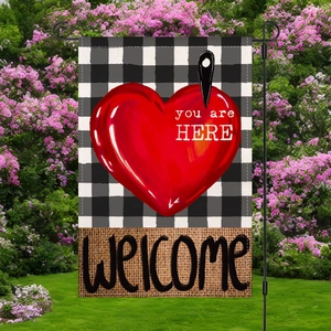 Bandera de jardín con corazón rojo y estaca de metal negro en un jardín floreciente
