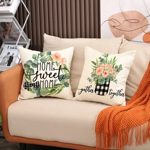 Detail of floral linen pillow covers with letter prints on a beige leather sofa