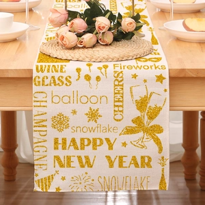 Close-up of linen Happy New Year table runner with gold glitter text and champagne icons