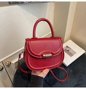 Close-up of red saddle bag with gold metal buckle and smooth leather texture on a sofa