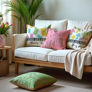 Vierteiliges Set Oster-Kissenbezüge mit Hasenmotiven auf einem weißen Sofa