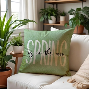 Green linen throw pillow with Spring is in the air text on a white sofa indoors