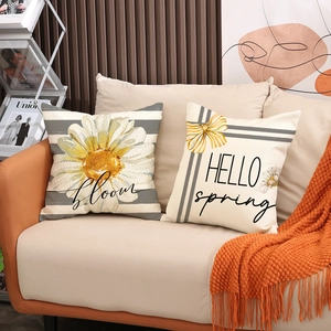 Spring daisy flower and letter print cushion covers set on a beige sofa with a knit throw