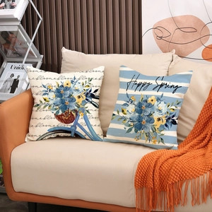 Détail de housses de coussin en lin à motifs floraux et vélo sur un canapé moderne
