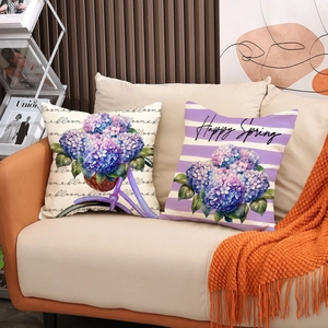 Détail de coussins en lin à fleurs sur un canapé beige avec une couverture orange douce