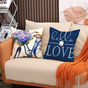 Detail view of linen pillow covers with bicycle and hello love prints on a leather sofa
