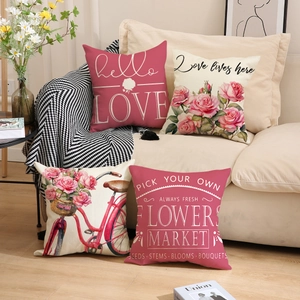 Close-up of four floral linen pillow covers with rose and bicycle prints on sofa