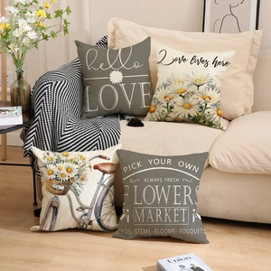 Detail of four linen pillow covers with flower patterns and vintage text on a sofa
