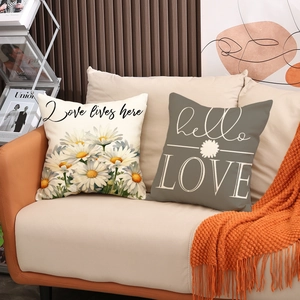 Close-up of linen pillow covers featuring daisy patterns and minimalist typography on sofa