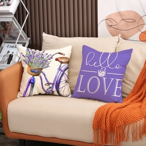 Detail of linen pillow covers with purple lavender bike and hello LOVE text on beige sofa