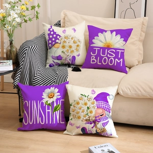 Detail of four purple linen pillow covers with daisy gnomes and text on a beige sofa