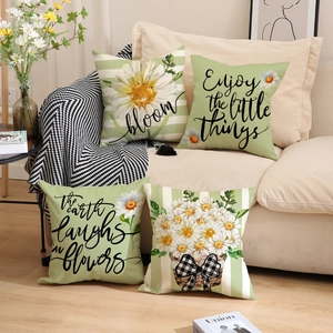 Detail of four linen cushion covers with daisy prints and checkered bows on a sofa