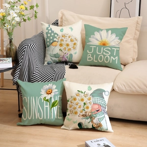 Detail of four linen cushion covers with gnomes and daisies on a beige sofa