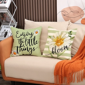 Detail of linen pillow covers with 'Enjoy the little things' text and daisy floral print