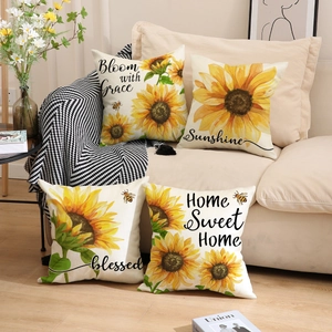 Detail of four sunflower pillow covers with Bloom with Grace text on cream sofa
