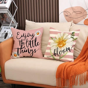 Close-up of linen pillow covers with Enjoy the Little Things text and daisy prints