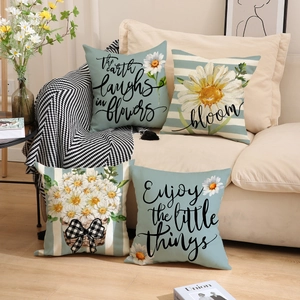 Close-up of linen pillow covers with daisy prints and blue stripes on a beige sofa
