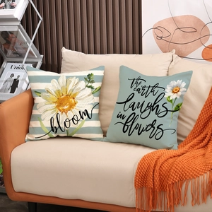 Linen throw pillow set with floral patterns and bloom text on a cozy beige sofa