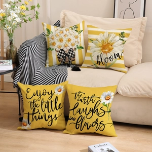 Detail view of four linen pillow covers with daisy floral patterns and yellow stripes