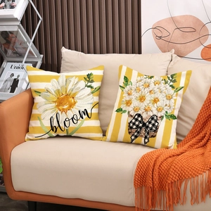 Close-up of decorative linen pillow covers with daisy prints and bloom text