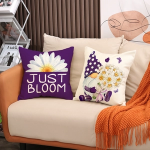 Detail of linen pillow covers with gnome and daisy prints on a beige fabric sofa