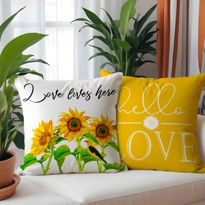 Set of two yellow and white linen pillows with sunflower prints on a white sofa