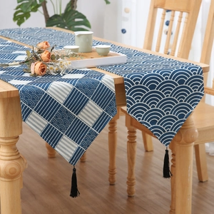 Blue and white table runner with wave pattern and tassels on a wooden tea table