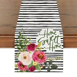 Detail eines geblümten Leinentischläufers mit Home Sweet Home-Text auf Holzhintergrund