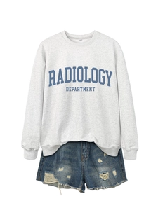 Detail of grey sweatshirt with Radiology Department print and distressed denim shorts