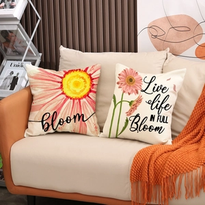 Detailed texture of daisy print linen cushions on a leather sofa with an orange throw