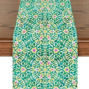 Detail of green floral vine table runner on dark wood surface with boho patterns