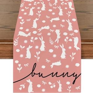 Detail of pink linen Easter table runner with bunny print and floral patterns on wood table