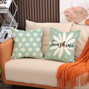 Set of 2 mint green daisy linen pillow covers with Sunshine text on a modern sofa