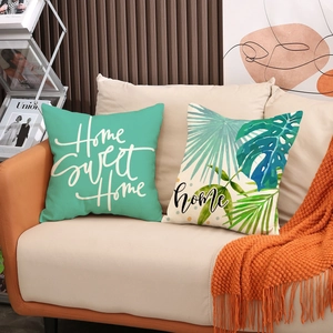 Set of two botanical leaf throw pillow covers with Home Sweet Home text on a sofa