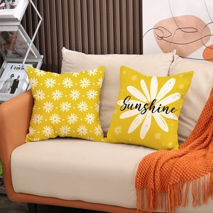 Detail of yellow linen pillowcases with white daisy print and Sunshine lettering on sofa