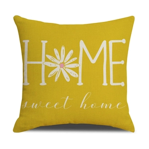 Close-up of ginger yellow linen pillowcase with white HOME sweet home text and daisy